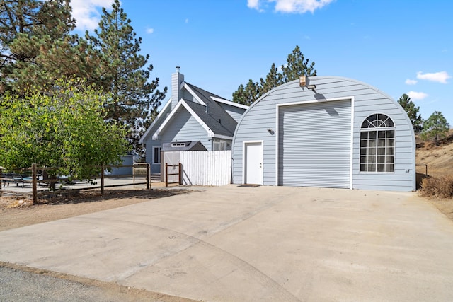 detached garage featuring fence and concrete driveway
