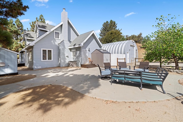 back of property featuring a storage shed, a patio area, an outdoor structure, and a chimney
