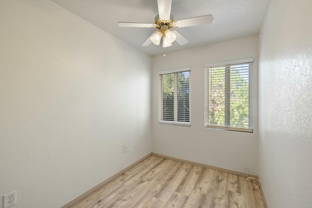 spare room featuring baseboards, light wood-type flooring, and ceiling fan