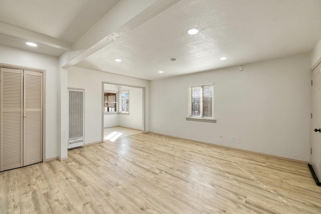 unfurnished bedroom with light wood finished floors, multiple windows, a textured ceiling, and baseboards