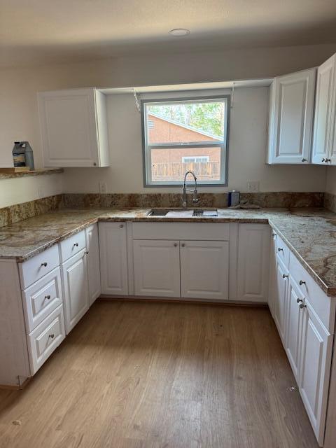 43427 Fairglen Rd, Lancaster, CA 93535 - kitchen with a sink, light wood finished floors, white cabinets, and light stone counters