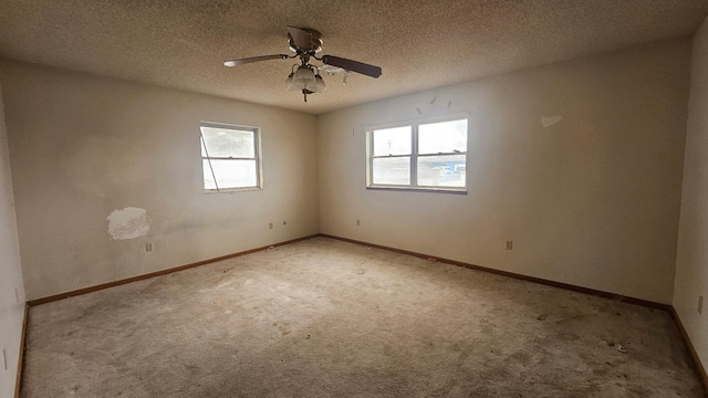 empty room with a textured ceiling, ceiling fan, carpet flooring, and baseboards