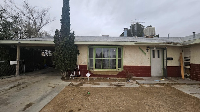 ranch-style home featuring concrete driveway, brick siding, central AC, and stucco siding