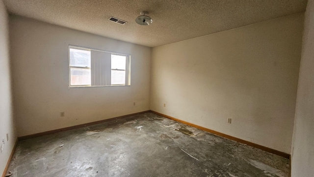 unfurnished room featuring visible vents, a textured ceiling, baseboards, and unfinished concrete floors