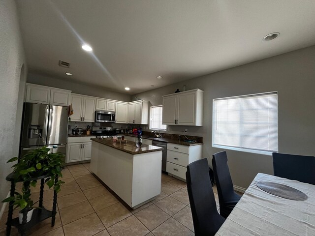 kitchen featuring sink, a center island, light tile patterned floors, white cabinets, and appliances with stainless steel finishes