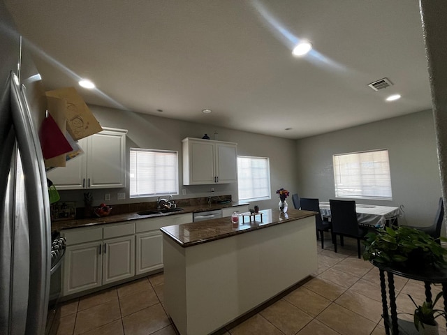 kitchen with a kitchen island, white cabinetry, sink, and light tile patterned floors