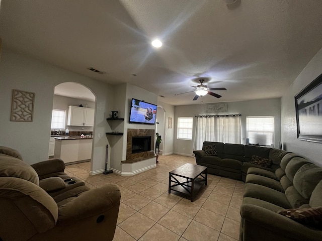 living room featuring ceiling fan, light tile patterned flooring, and a textured ceiling