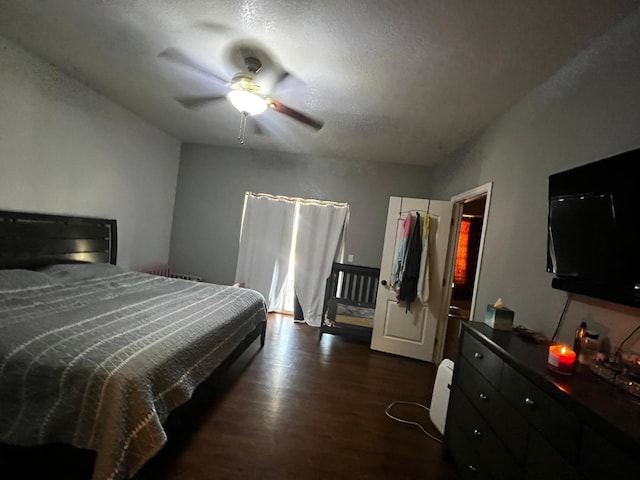 bedroom with a textured ceiling, ceiling fan, and dark hardwood / wood-style floors