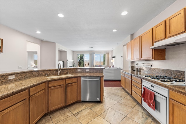 kitchen with a sink, white appliances, brown cabinetry, recessed lighting, and under cabinet range hood