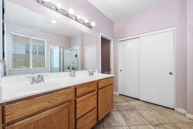 bathroom with a sink, baseboards, a shower stall, and double vanity