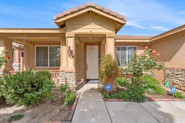 entrance to property featuring stone siding and stucco siding