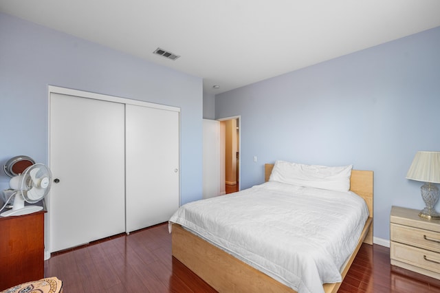 bedroom with a closet, wood finished floors, and visible vents