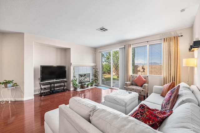 living room featuring visible vents, baseboards, wood finished floors, and a fireplace