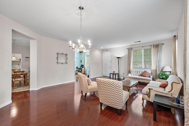 living area featuring baseboards, a notable chandelier, wood finished floors, and visible vents
