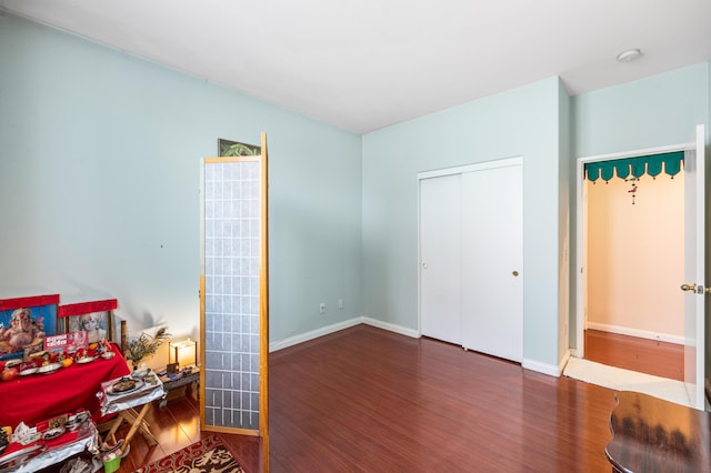 bedroom featuring baseboards, wood finished floors, and a closet