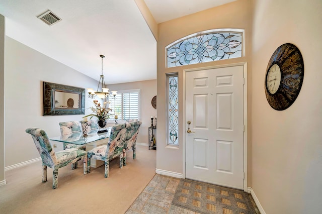 foyer with light colored carpet, lofted ceiling, and an inviting chandelier