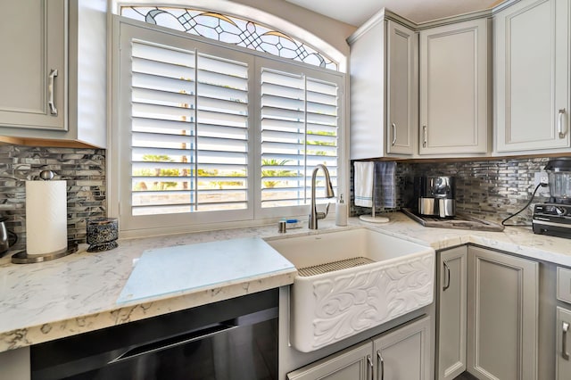 kitchen with backsplash, gray cabinets, light stone countertops, and sink