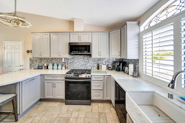 kitchen with lofted ceiling, hanging light fixtures, sink, decorative backsplash, and appliances with stainless steel finishes