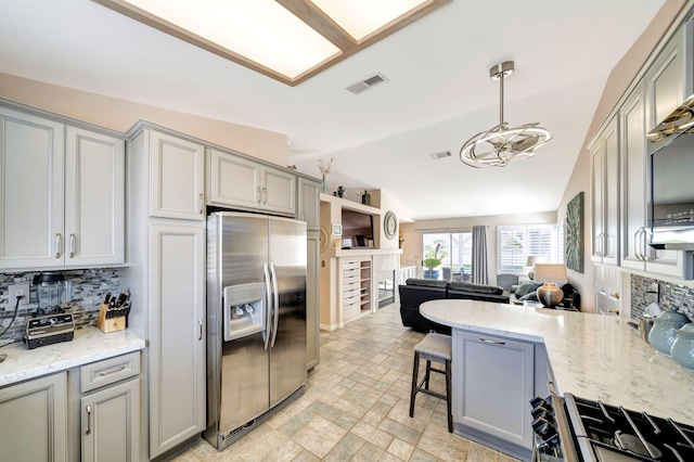 kitchen featuring a breakfast bar, lofted ceiling, stainless steel refrigerator with ice dispenser, tasteful backsplash, and decorative light fixtures