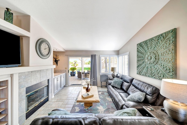 living room with lofted ceiling and a tiled fireplace