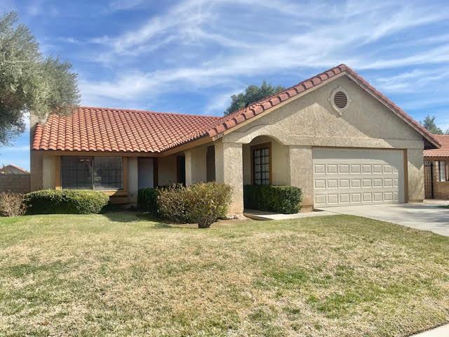 mediterranean / spanish house with a garage, a front lawn, concrete driveway, and a tiled roof