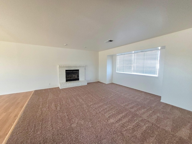 unfurnished living room with a fireplace and carpet