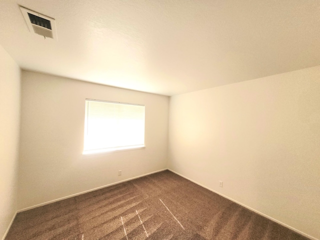 spare room with dark colored carpet