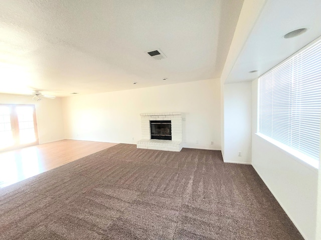 unfurnished living room featuring carpet flooring, a brick fireplace, and ceiling fan