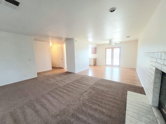 unfurnished living room featuring carpet flooring, ceiling fan, and a brick fireplace