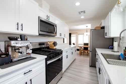 45522 Andale Ave, Lancaster, CA 93535 - kitchen with appliances with stainless steel finishes, white cabinetry, a sink, light countertops, and light wood finished floors