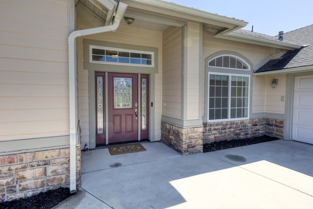 24500 Jacaranda Dr, Tehachapi, CA 93561 - view of exterior entry featuring a shingled roof, stone siding, concrete driveway, and an attached garage