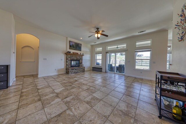 24500 Jacaranda Dr, Tehachapi, CA 93561 - living area featuring a ceiling fan, baseboards, arched walkways, a glass covered fireplace, and stone tile flooring