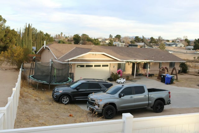 single story home with a garage and a trampoline