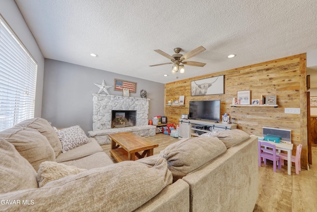 20412 El Porto Ct, Tehachapi, CA 93561 - living room featuring wood walls, a fireplace, light wood finished floors, ceiling fan, and a textured ceiling