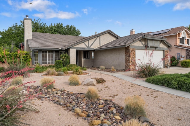 44055 Colony Dr, Lancaster, CA 93536 - view of front facade with stucco siding, an attached garage, a chimney, and driveway