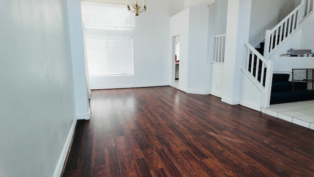 unfurnished room with dark wood-type flooring, a high ceiling, and a chandelier