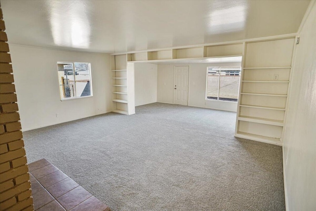 unfurnished living room with built in shelves and carpet