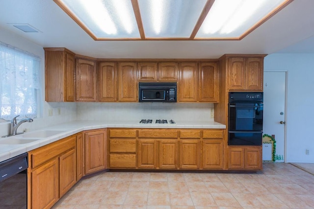 kitchen with a warming drawer, brown cabinetry, a sink, and black appliances