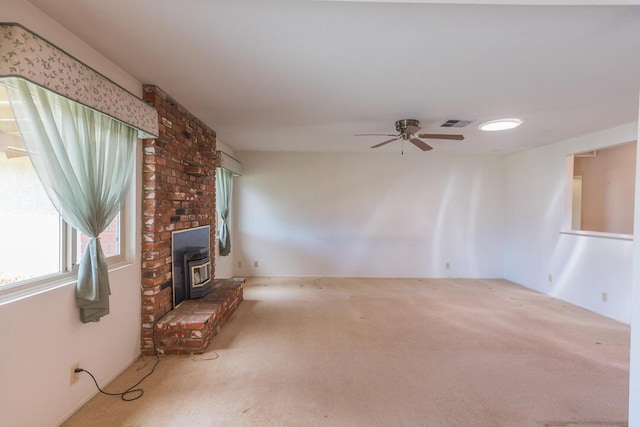 unfurnished living room with a wood stove, carpet, and a ceiling fan