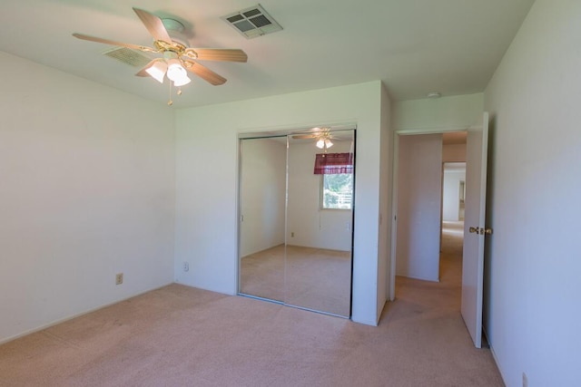 unfurnished bedroom featuring a closet, a ceiling fan, light colored carpet, and visible vents