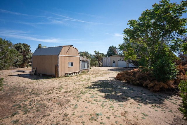 view of home's exterior with a gambrel roof and an outbuilding