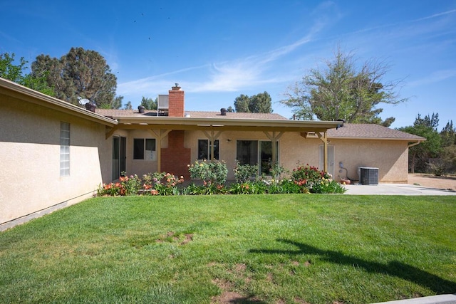 rear view of property featuring a lawn, central air condition unit, stucco siding, and a chimney