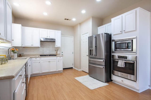2447 Brompton Ct, Palmdale, CA 93551 - kitchen featuring stainless steel appliances, a sink, light wood finished floors, decorative backsplash, and white cabinets