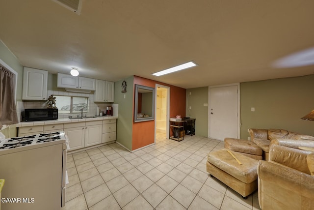 19426 Cavalier Ct, Tehachapi, CA 93561 - kitchen with black microwave, white gas stove, white cabinets, and light tile patterned flooring