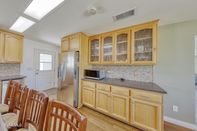 19426 Cavalier Ct, Tehachapi, CA 93561 - kitchen with appliances with stainless steel finishes, light brown cabinetry, decorative backsplash, light wood-style floors, and glass insert cabinets