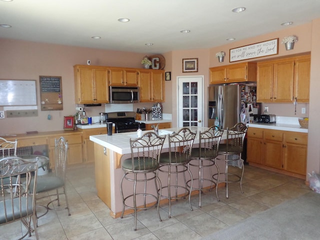 kitchen featuring appliances with stainless steel finishes, a center island, light tile patterned floors, and a kitchen breakfast bar