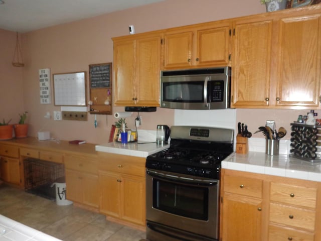 kitchen featuring appliances with stainless steel finishes, tile countertops, and light tile patterned floors