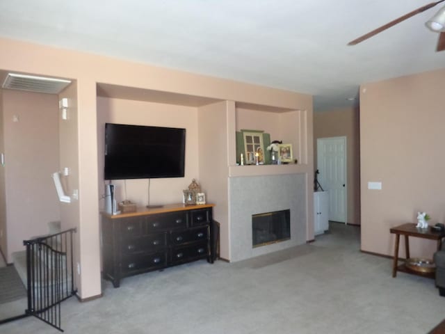 carpeted living room featuring a tiled fireplace and ceiling fan