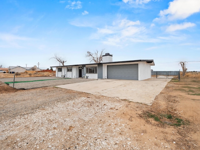 single story home with a chimney, concrete driveway, an attached garage, and fence