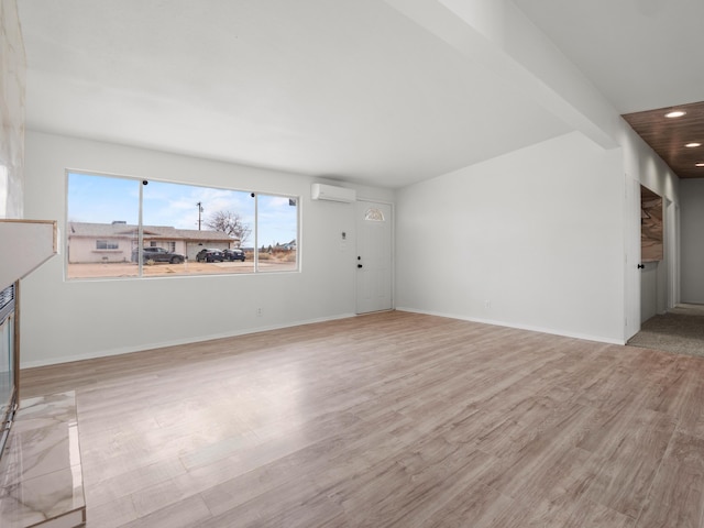 unfurnished living room featuring light wood finished floors, recessed lighting, baseboards, and a wall unit AC